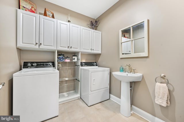 laundry area with cabinets, light tile patterned floors, sink, and washing machine and dryer