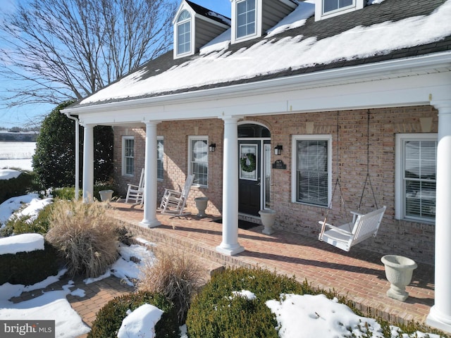 snow covered property entrance with a porch