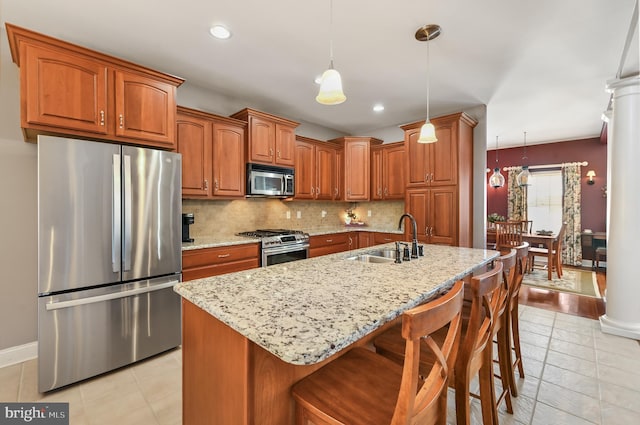 kitchen with sink, pendant lighting, appliances with stainless steel finishes, and an island with sink