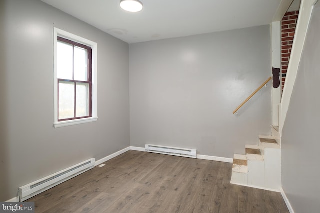 empty room with hardwood / wood-style flooring and a baseboard heating unit