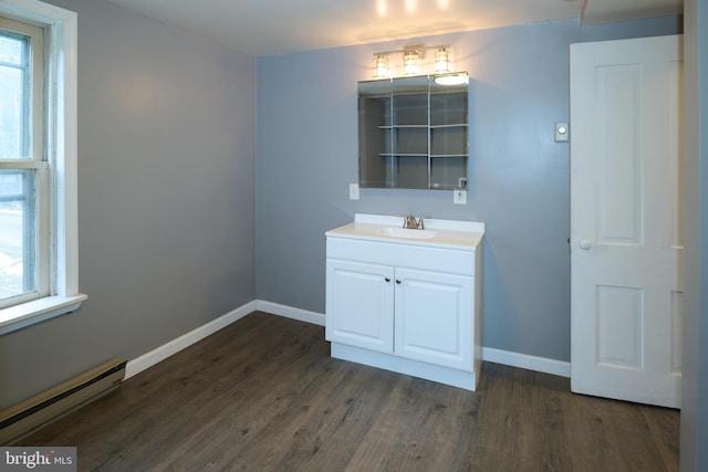 bathroom featuring baseboard heating, hardwood / wood-style flooring, a wealth of natural light, and vanity