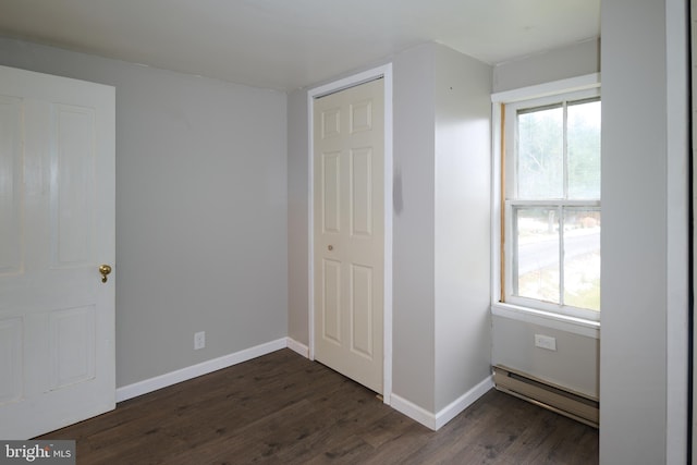 unfurnished bedroom with a baseboard radiator, a closet, and dark hardwood / wood-style floors