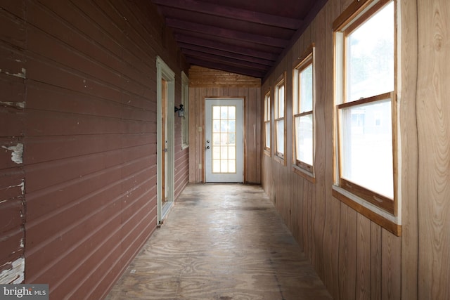 hallway with wood walls and vaulted ceiling