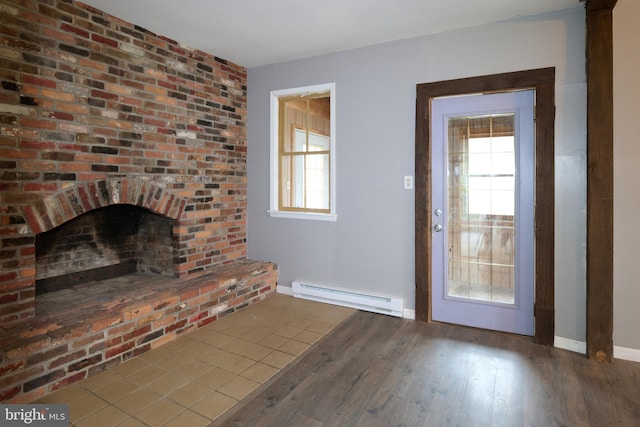 unfurnished living room with wood-type flooring, a baseboard radiator, and a brick fireplace