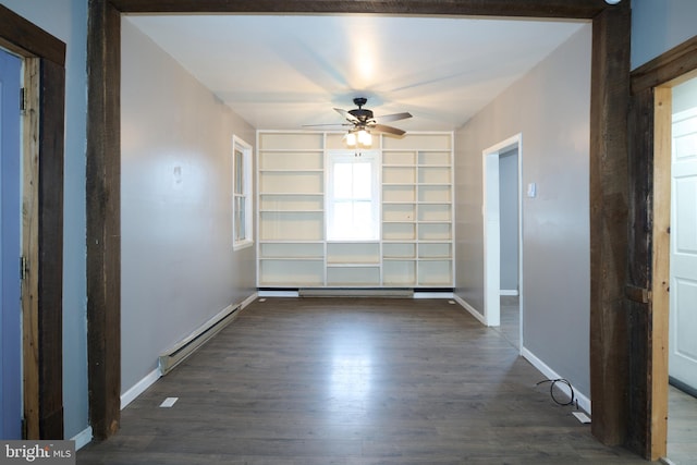 empty room with ceiling fan, dark hardwood / wood-style flooring, a baseboard radiator, and built in shelves