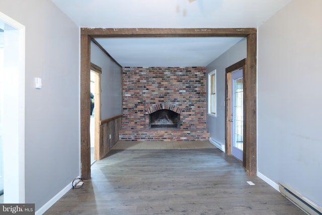 unfurnished living room featuring a fireplace, baseboard heating, hardwood / wood-style flooring, and beamed ceiling