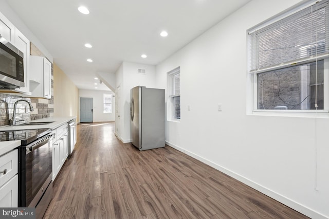 kitchen featuring sink, appliances with stainless steel finishes, white cabinetry, backsplash, and dark hardwood / wood-style flooring