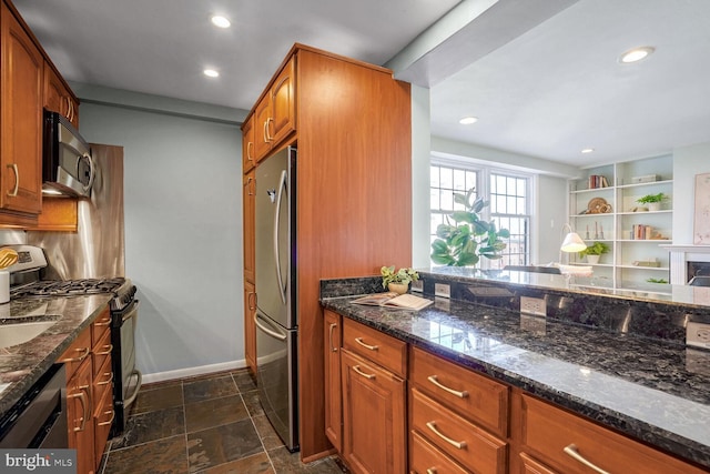 kitchen featuring stainless steel appliances, dark stone counters, and backsplash