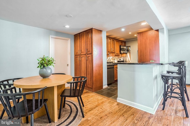 kitchen featuring wood-type flooring, a breakfast bar area, kitchen peninsula, and appliances with stainless steel finishes