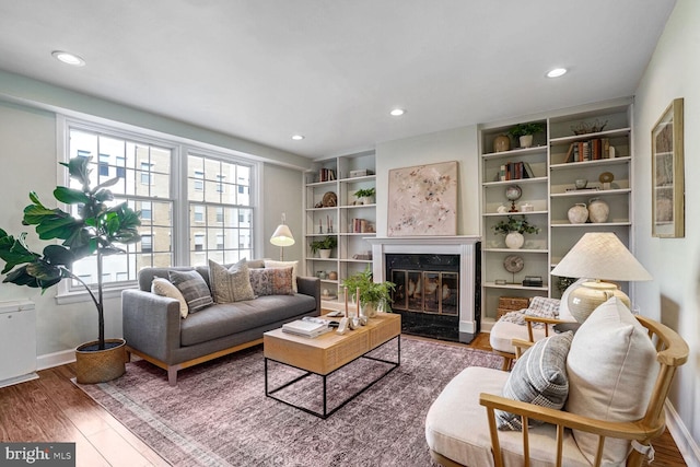 living room with hardwood / wood-style floors, built in features, and a fireplace