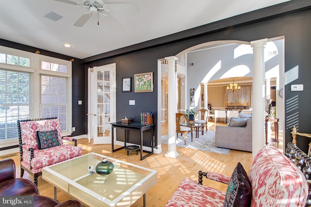 living area featuring light wood finished floors, arched walkways, and ornate columns