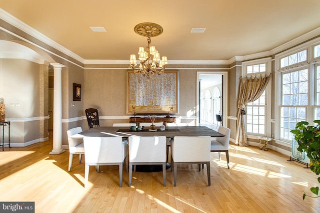 dining space with visible vents, light wood finished floors, decorative columns, arched walkways, and a chandelier