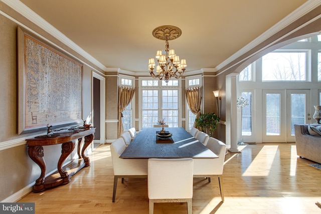 dining room featuring a chandelier, arched walkways, light wood-style floors, and ornamental molding