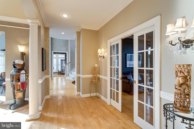 hallway featuring baseboards, ornate columns, ornamental molding, french doors, and light wood-type flooring