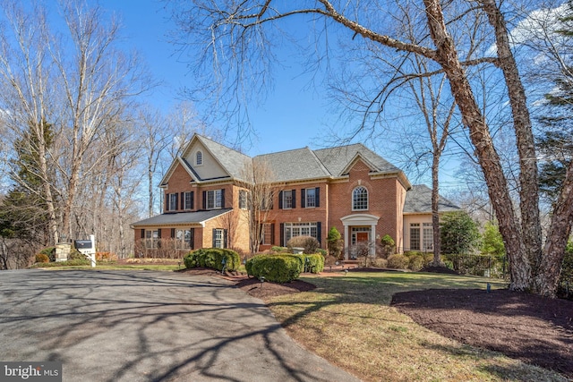 colonial home with brick siding and a front yard