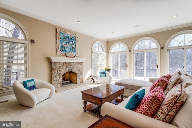 living area featuring a wealth of natural light, a stone fireplace, and carpet floors