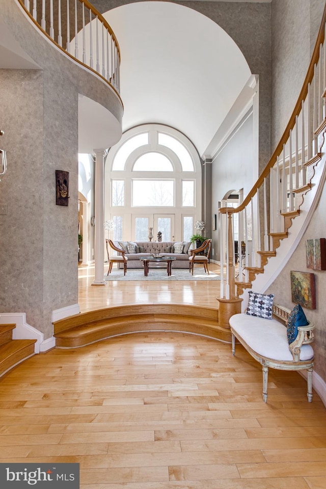 entryway with a towering ceiling, stairs, ornate columns, and hardwood / wood-style flooring