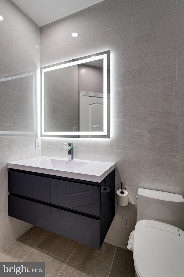 bathroom with tile patterned flooring, toilet, tile walls, and vanity