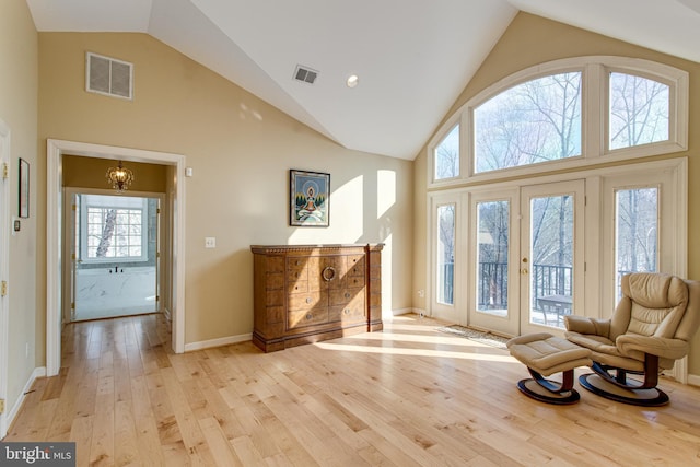 foyer entrance featuring visible vents, high vaulted ceiling, light wood-style floors, and an inviting chandelier