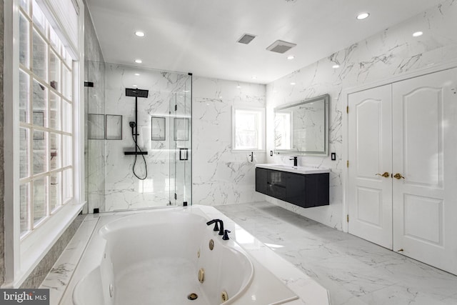 bathroom with marble finish floor, stone wall, vanity, and a tub with jets