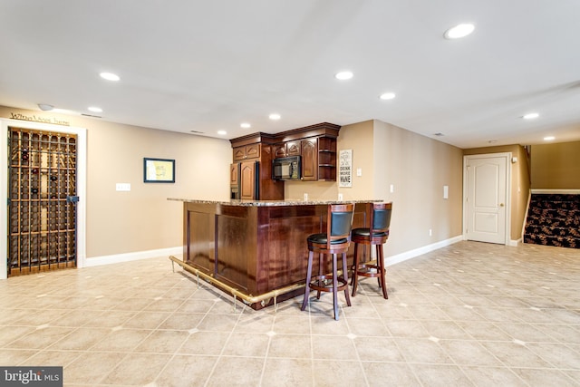 bar featuring baseboards, indoor bar, black microwave, recessed lighting, and refrigerator