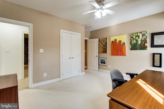 office featuring light colored carpet, a ceiling fan, and baseboards