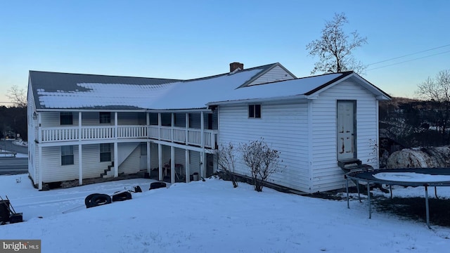 snow covered back of property featuring a trampoline