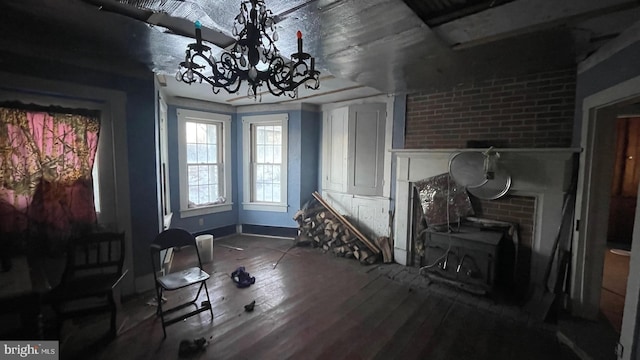 interior space with wood-type flooring, a wood stove, and a notable chandelier