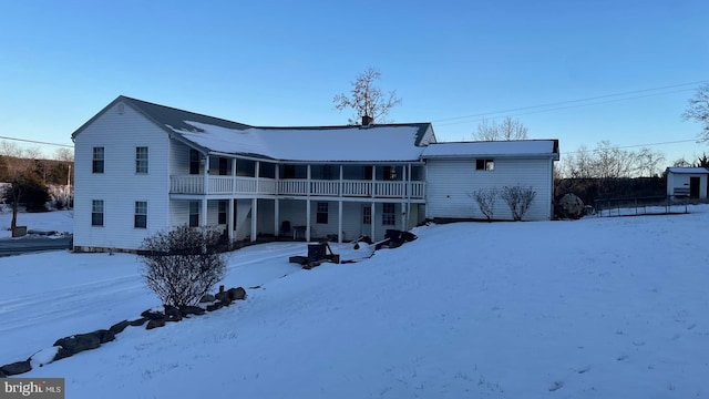 snow covered house featuring a balcony