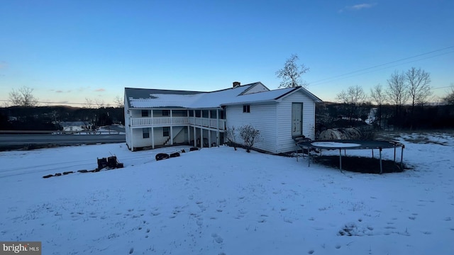 snow covered back of property featuring a trampoline