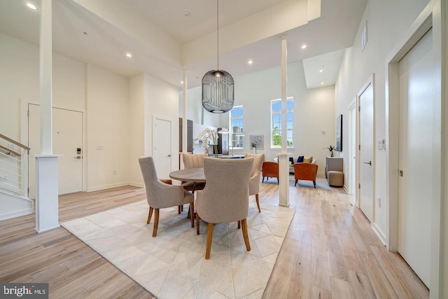 dining space featuring a towering ceiling and light hardwood / wood-style floors