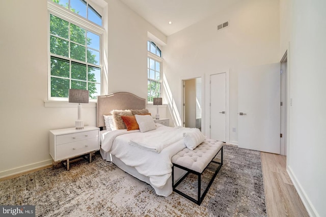 bedroom featuring a towering ceiling and light hardwood / wood-style floors