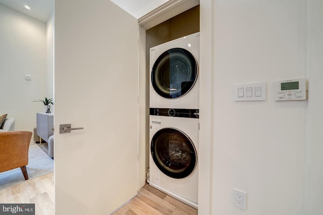 laundry room with light hardwood / wood-style flooring and stacked washing maching and dryer