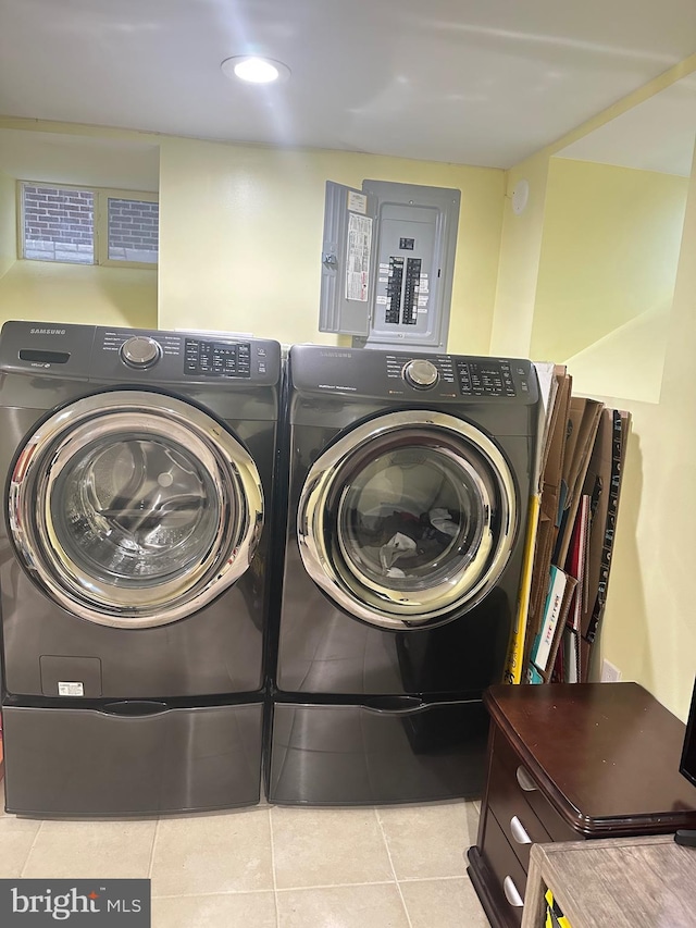 washroom featuring electric panel, light tile patterned floors, and washer and clothes dryer