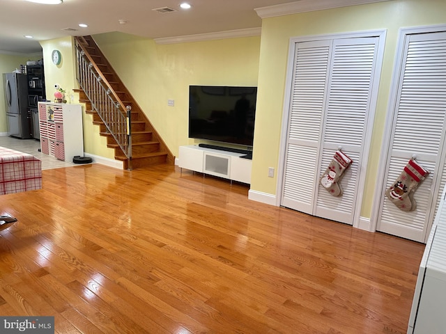 living room with light hardwood / wood-style flooring and crown molding