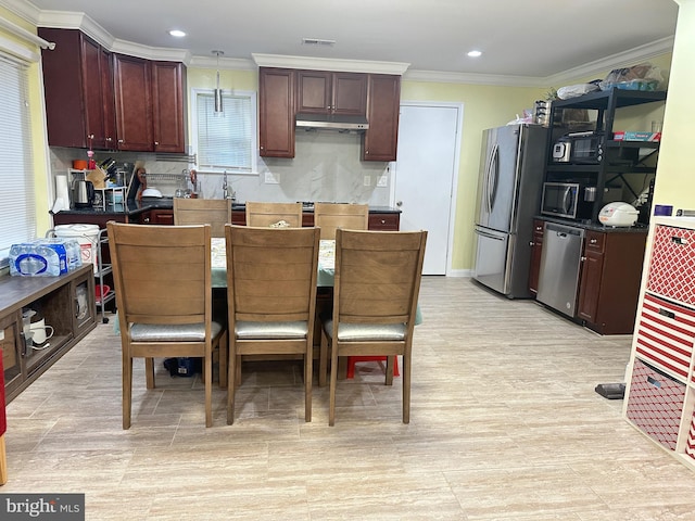 kitchen with stainless steel appliances, ornamental molding, and hanging light fixtures