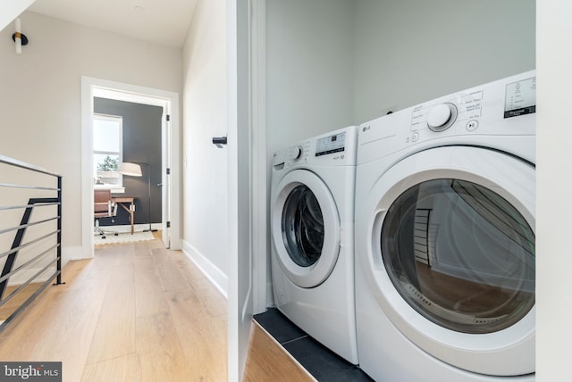 washroom with hardwood / wood-style floors and washing machine and clothes dryer