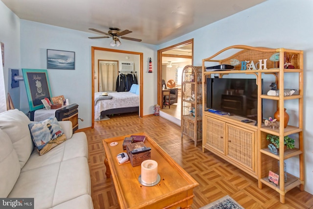 living room with a wall mounted AC, light parquet floors, and ceiling fan