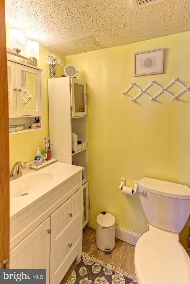 bathroom with toilet, hardwood / wood-style flooring, and vanity