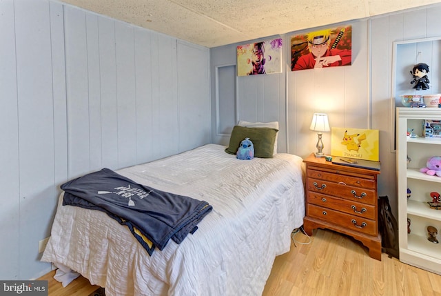 bedroom featuring wood walls and light hardwood / wood-style floors