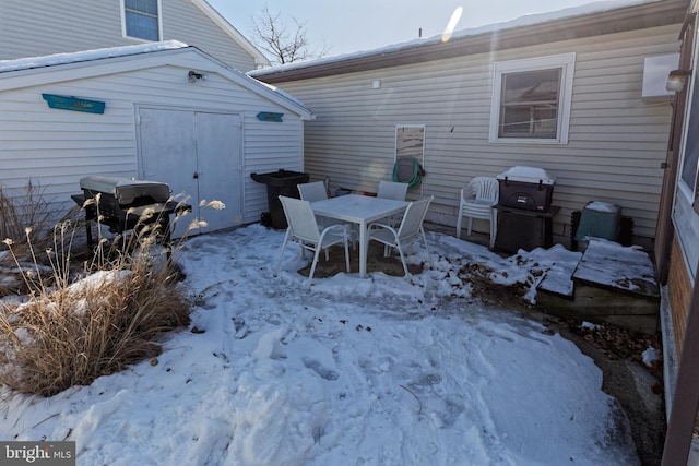 snow covered patio with a shed and grilling area