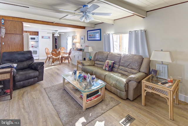 living room with ceiling fan, light wood-type flooring, and beamed ceiling