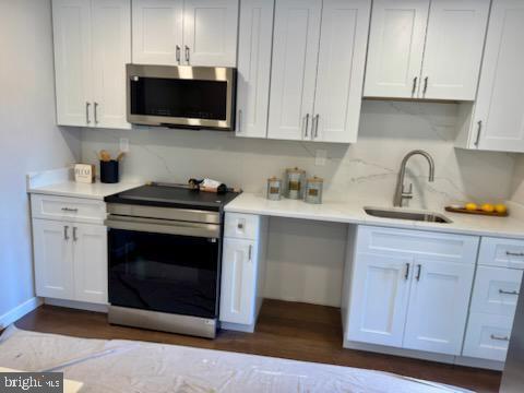 kitchen with sink, dark wood-type flooring, white cabinets, and appliances with stainless steel finishes