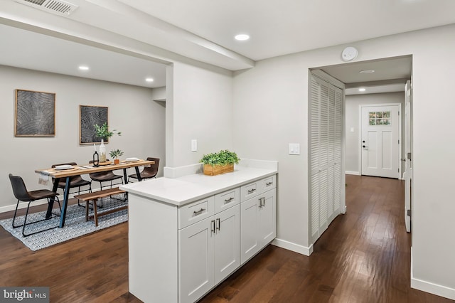 kitchen featuring dark wood-type flooring, kitchen peninsula, and white cabinets