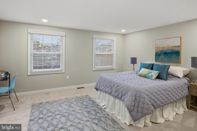 bedroom with multiple windows and light carpet