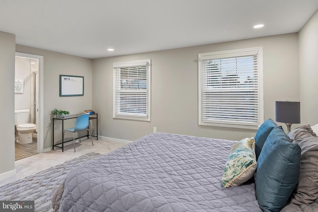 bedroom featuring connected bathroom and light colored carpet