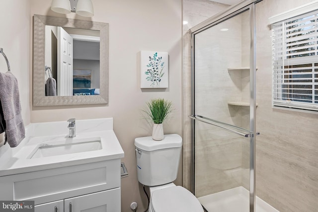 bathroom featuring a shower with door, vanity, and toilet