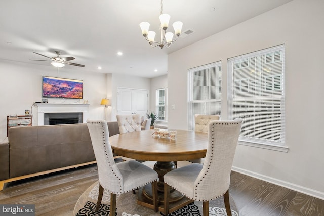 dining space featuring ceiling fan with notable chandelier and dark hardwood / wood-style flooring