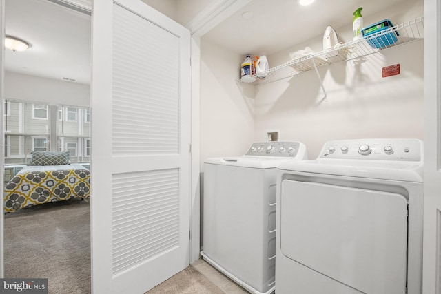 laundry area featuring washer and clothes dryer and light carpet