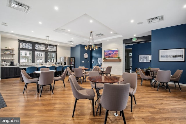 dining room with light hardwood / wood-style floors and a raised ceiling